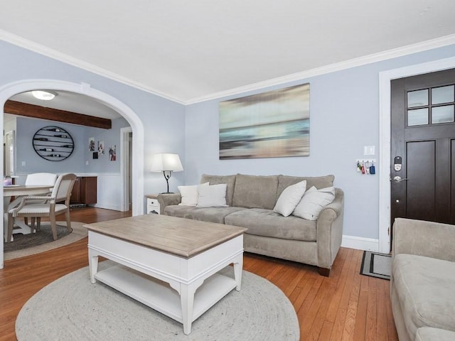 living room featuring hardwood / wood-style flooring, baseboards, arched walkways, and ornamental molding