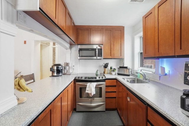 6 Brigham St Unit 2, Boston, MA 02128 - kitchen featuring appliances with stainless steel finishes, a sink, light countertops, and brown cabinets