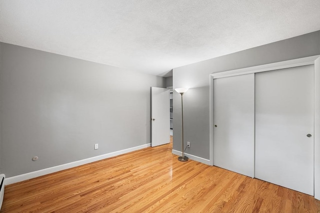 11 Cogswell Ave Unit 16, Cambridge, MA 02140 - unfurnished bedroom featuring light wood-style flooring, a closet, baseboard heating, baseboards, and a textured ceiling