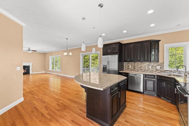 kitchen with stainless steel appliances, a sink, crown molding, backsplash, and baseboards