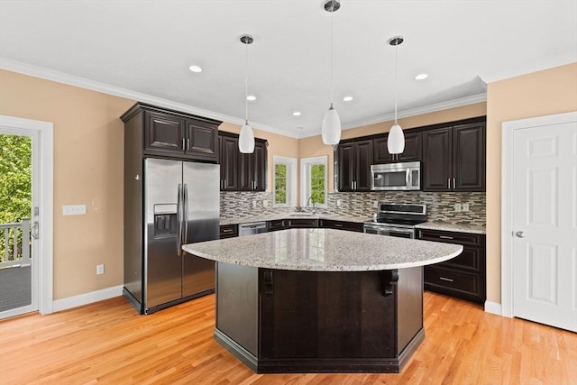 kitchen featuring stainless steel appliances, decorative backsplash, plenty of natural light, a sink, and crown molding