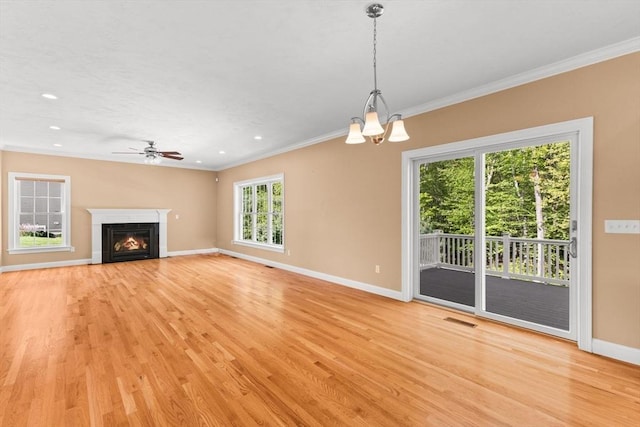 unfurnished living room featuring crown molding, baseboards, light wood-type flooring, a chandelier, and ceiling fan