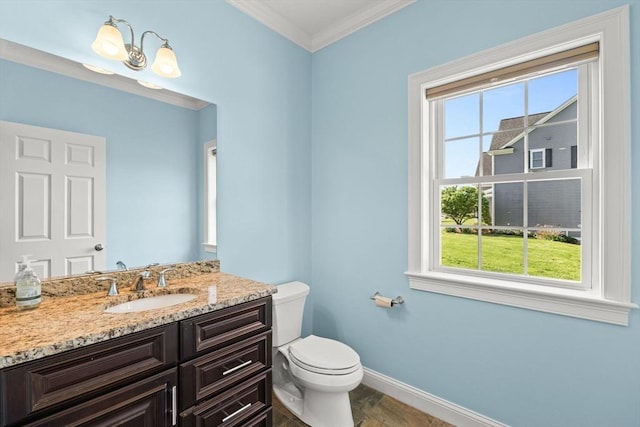 bathroom with healthy amount of natural light, baseboards, toilet, ornamental molding, and vanity