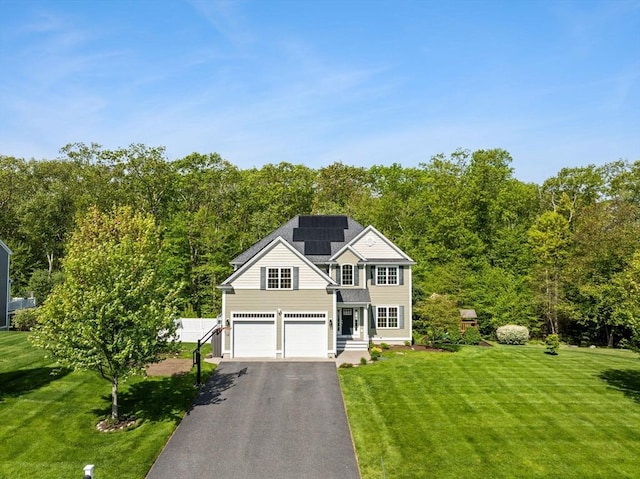 traditional home with asphalt driveway, a front lawn, an attached garage, and solar panels
