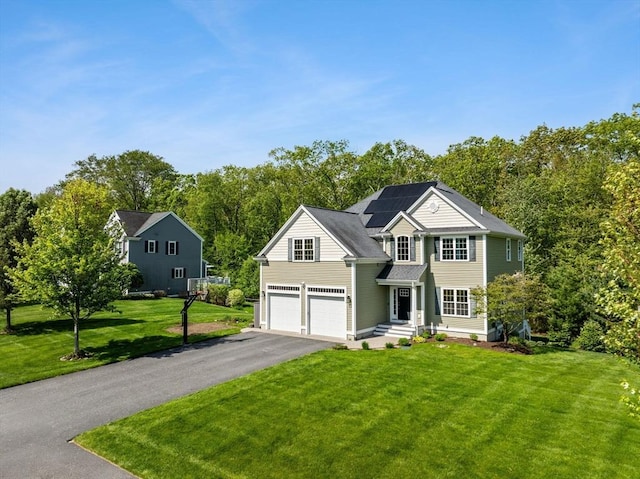 traditional-style house featuring driveway, roof mounted solar panels, a front yard, and a garage