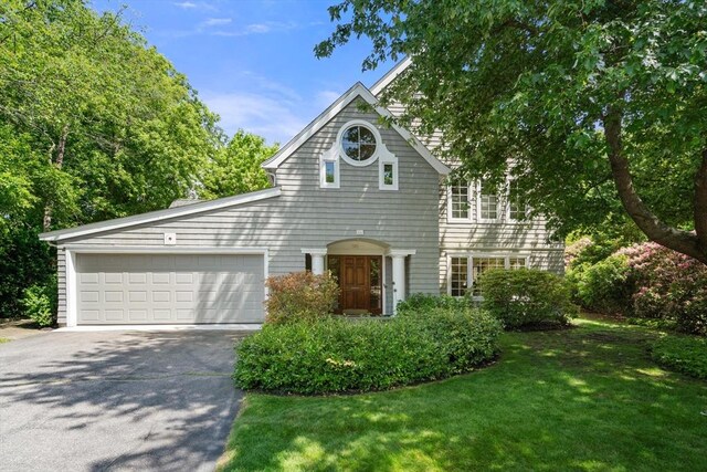 shingle-style home featuring a front yard, an attached garage, and driveway
