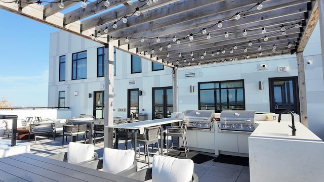 view of patio / terrace featuring exterior kitchen, a pergola, and a grill