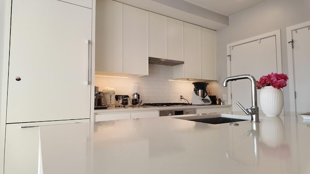 kitchen with decorative backsplash, sink, white cabinets, and gas cooktop