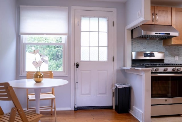 62 Roberts Dr Unit 62, Bedford, MA 01730 - kitchen featuring stainless steel gas range, wall chimney exhaust hood, tasteful backsplash, light wood-style floors, and healthy amount of natural light
