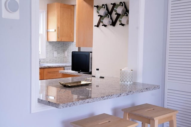 62 Roberts Dr Unit 62, Bedford, MA 01730 - kitchen featuring light brown cabinets, tasteful backsplash, light stone countertops, and a peninsula