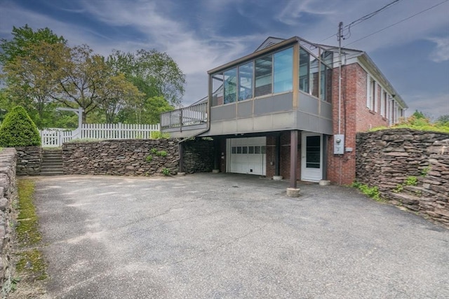 5 Norman Cir, Montague, MA 01376 - view of property exterior with brick siding, an attached garage, asphalt driveway, and a sunroom