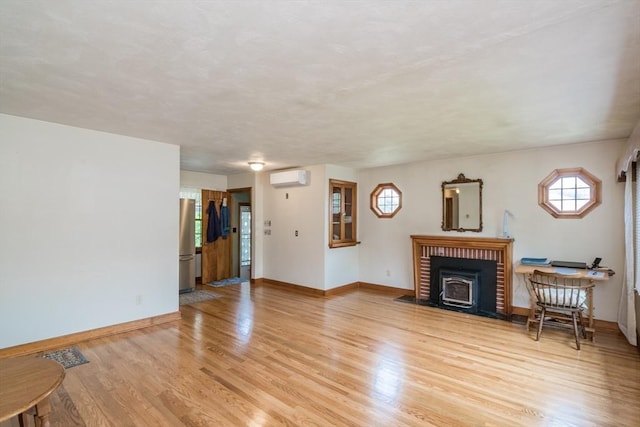 5 Norman Cir, Montague, MA 01376 - unfurnished living room with a wall mounted air conditioner, a wood stove, and light wood finished floors