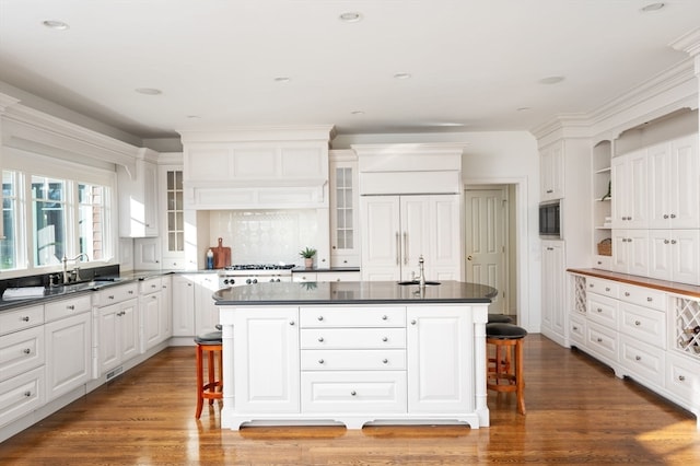 kitchen featuring a center island with sink, dark hardwood / wood-style floors, and a kitchen bar