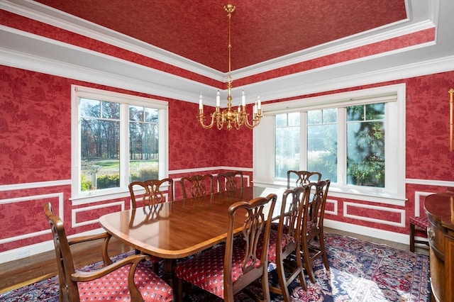 dining room featuring a chandelier, hardwood / wood-style floors, a raised ceiling, and ornamental molding