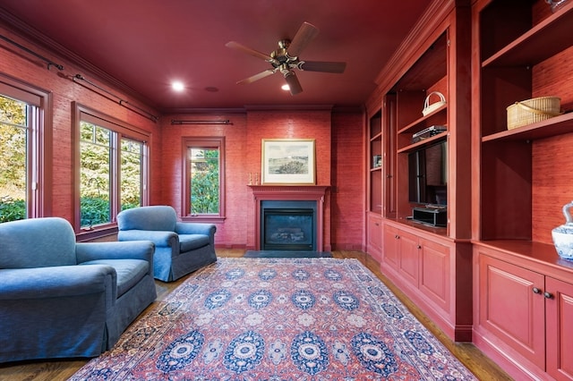 living room with ceiling fan, built in features, ornamental molding, and light hardwood / wood-style flooring