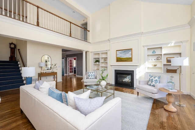 living room featuring decorative columns, built in shelves, hardwood / wood-style floors, and high vaulted ceiling