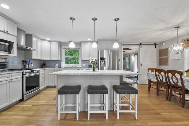 74 S Douglas St, Rockland, MA 02370 - kitchen with stainless steel appliances, wall chimney range hood, a barn door, tasteful backsplash, and recessed lighting