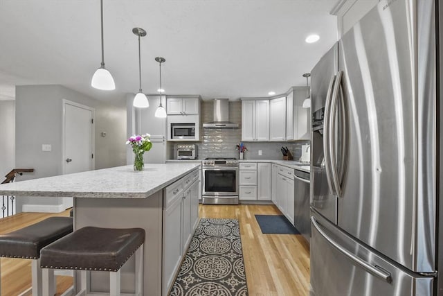 74 S Douglas St, Rockland, MA 02370 - kitchen featuring appliances with stainless steel finishes, wall chimney exhaust hood, a center island, tasteful backsplash, and light wood finished floors
