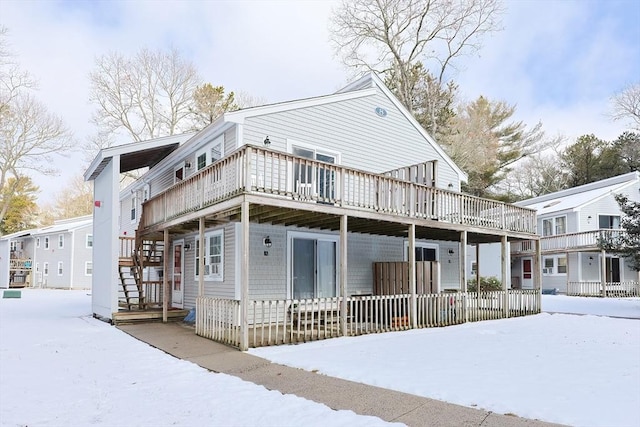 snow covered rear of property with a wooden deck