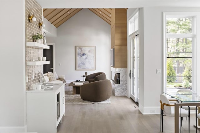interior space with wooden ceiling, baseboards, high vaulted ceiling, and light wood-style floors