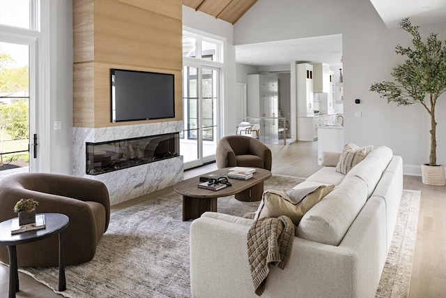 living room featuring high vaulted ceiling, a high end fireplace, and wood finished floors
