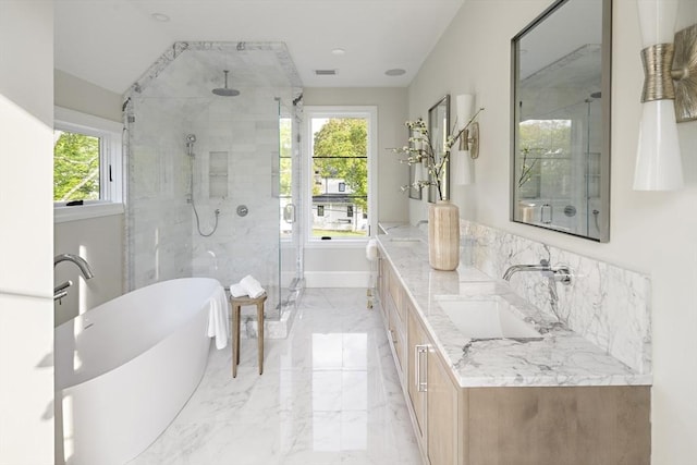full bath with a freestanding tub, marble finish floor, a stall shower, and a sink