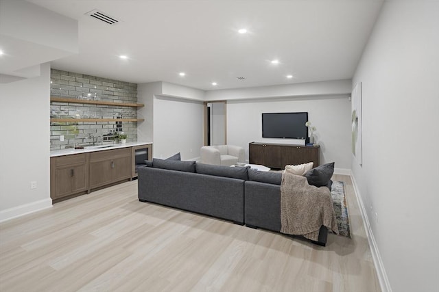 living area with light wood-style flooring, wet bar, visible vents, and recessed lighting