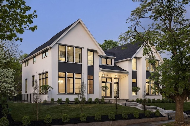 rear view of house with a lawn and stucco siding
