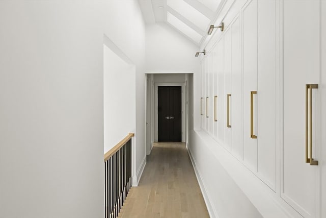 hallway with vaulted ceiling and light wood-style flooring