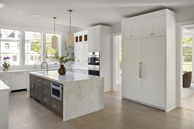 kitchen with light wood-type flooring, stainless steel appliances, and white cabinetry