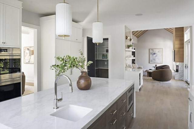 kitchen featuring light stone countertops, white cabinetry, appliances with stainless steel finishes, and a sink