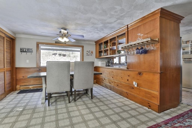 dining room with ceiling fan, wood walls, and sink