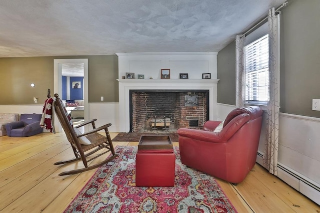 living room with baseboard heating, a textured ceiling, and light hardwood / wood-style flooring