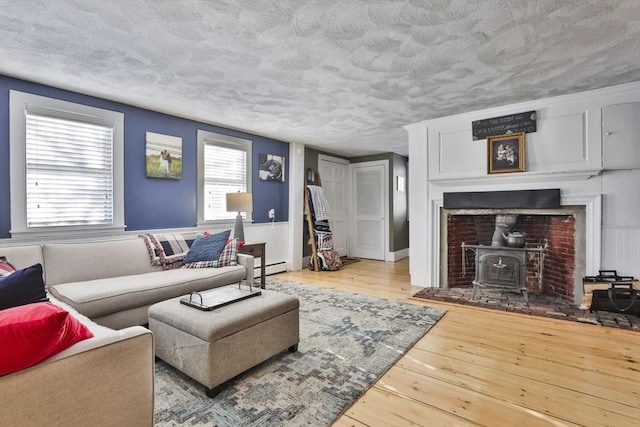 living room with a baseboard radiator, a wood stove, and light hardwood / wood-style floors