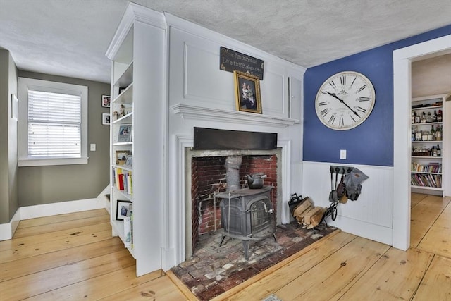 room details with a wood stove, hardwood / wood-style floors, a textured ceiling, and wooden walls