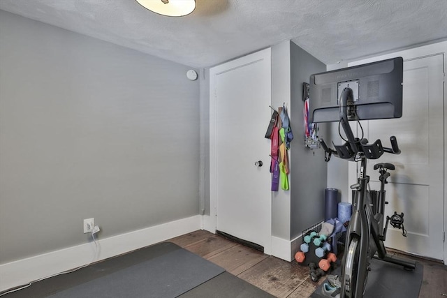 exercise room with a textured ceiling and dark hardwood / wood-style flooring