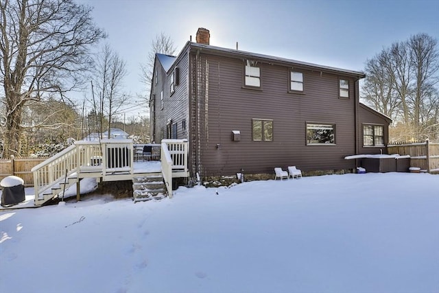 snow covered back of property featuring a deck