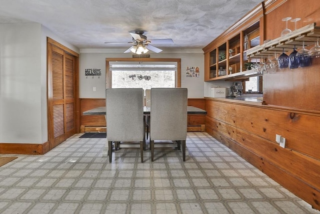 unfurnished dining area featuring ceiling fan and wood walls