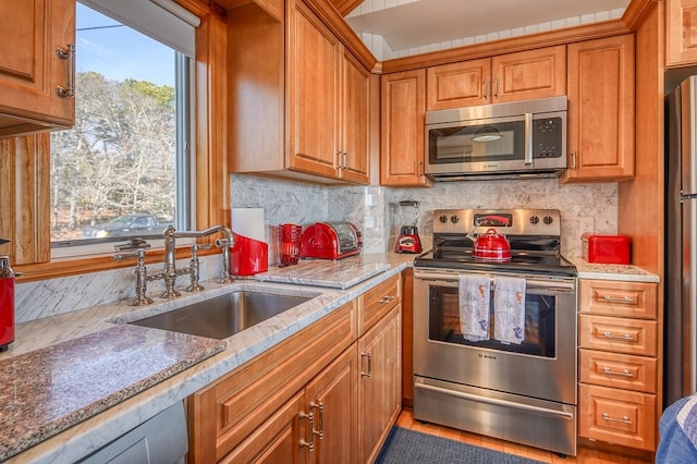 kitchen featuring appliances with stainless steel finishes, a wealth of natural light, tasteful backsplash, and sink