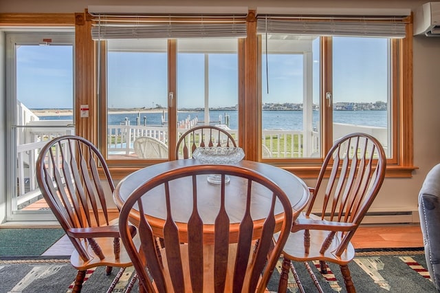 sunroom with a water view, a wealth of natural light, a baseboard heating unit, and a wall mounted AC