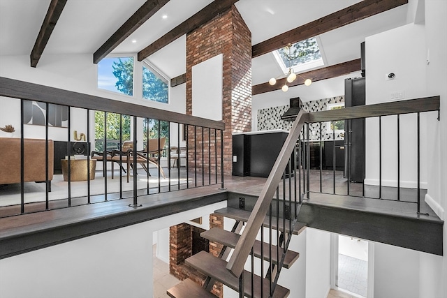 staircase with a skylight, high vaulted ceiling, and beamed ceiling