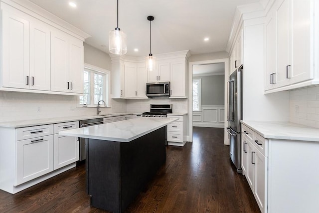 kitchen featuring light stone counters, decorative light fixtures, a kitchen island, stainless steel appliances, and white cabinets