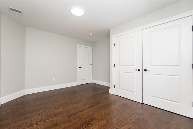 unfurnished bedroom featuring dark wood-type flooring and a closet