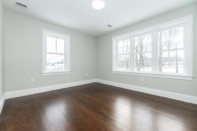 spare room featuring dark hardwood / wood-style flooring and plenty of natural light