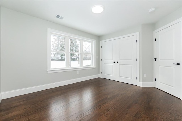 unfurnished bedroom with dark hardwood / wood-style flooring and a closet