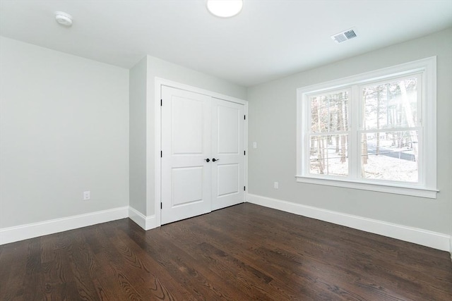 unfurnished bedroom with dark hardwood / wood-style floors and a closet