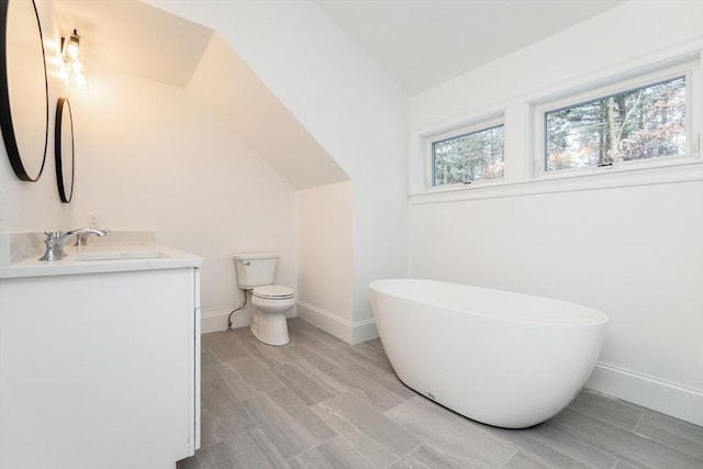 bathroom with a tub to relax in, vanity, toilet, and vaulted ceiling