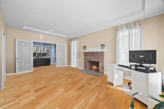 home office with a fireplace, a raised ceiling, and light wood-type flooring