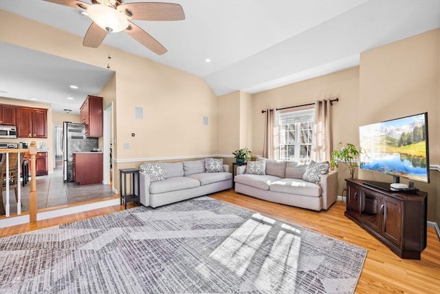 living room featuring vaulted ceiling, ceiling fan, and light wood-type flooring