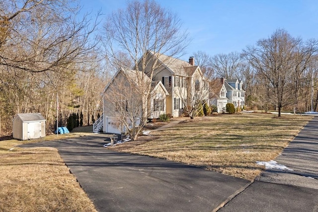 view of front of property with a balcony, a front lawn, and a storage shed